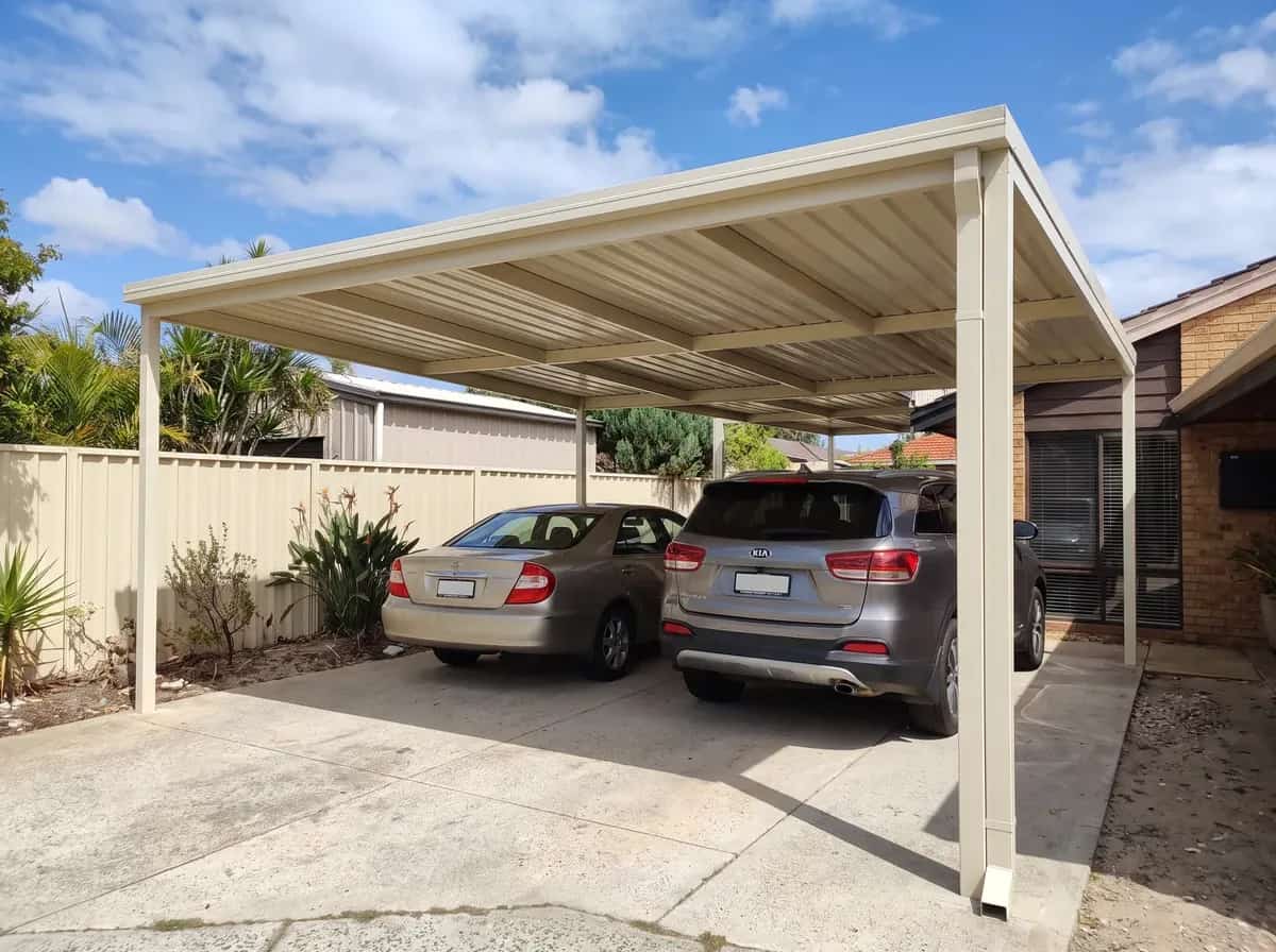 A double Colorbond carport in charcoal steel over a driveway at a Perth home, late afternoon