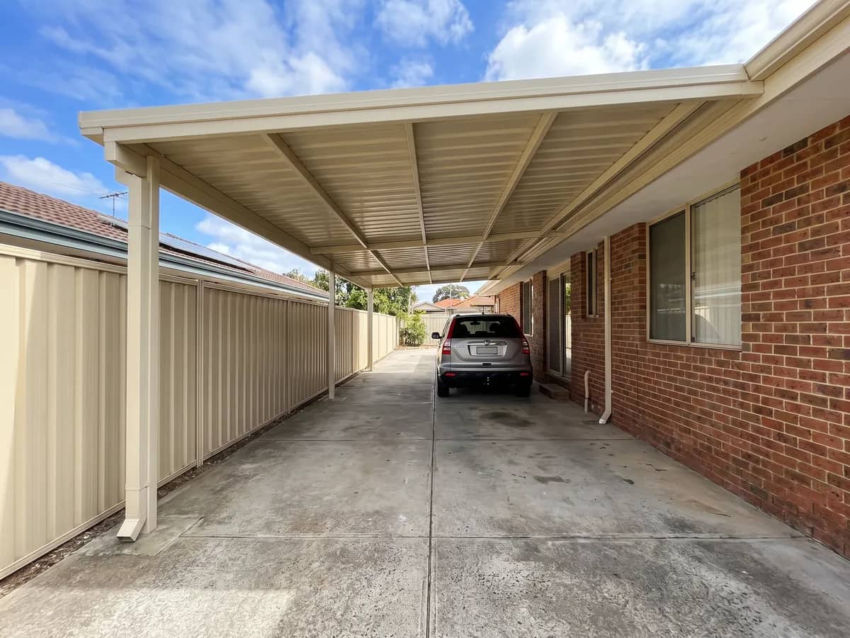 A flat-roof carport with a low fall away from the house