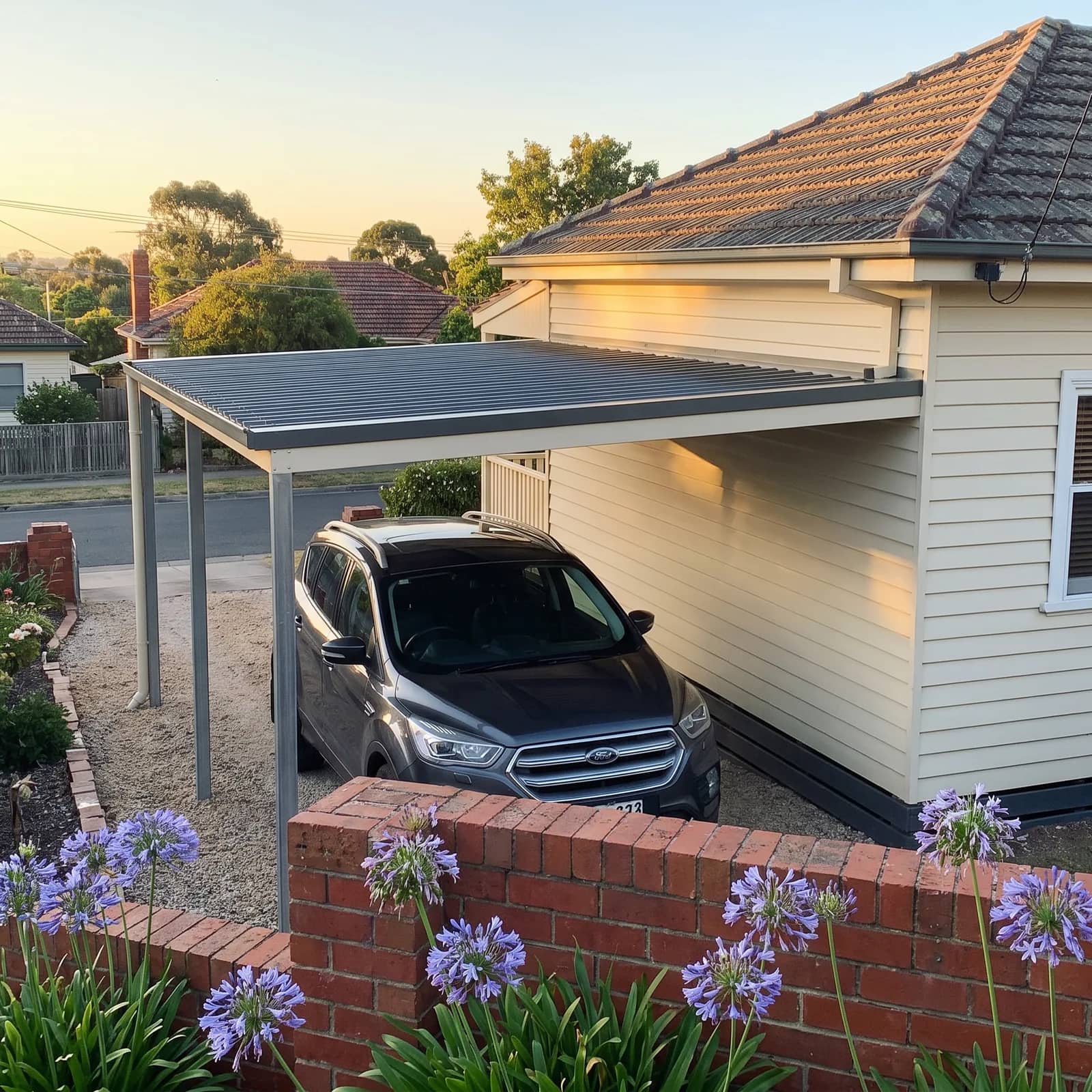 A raised flat carport beside a Perth home, its single roof plane sloping down from the house to the outer posts