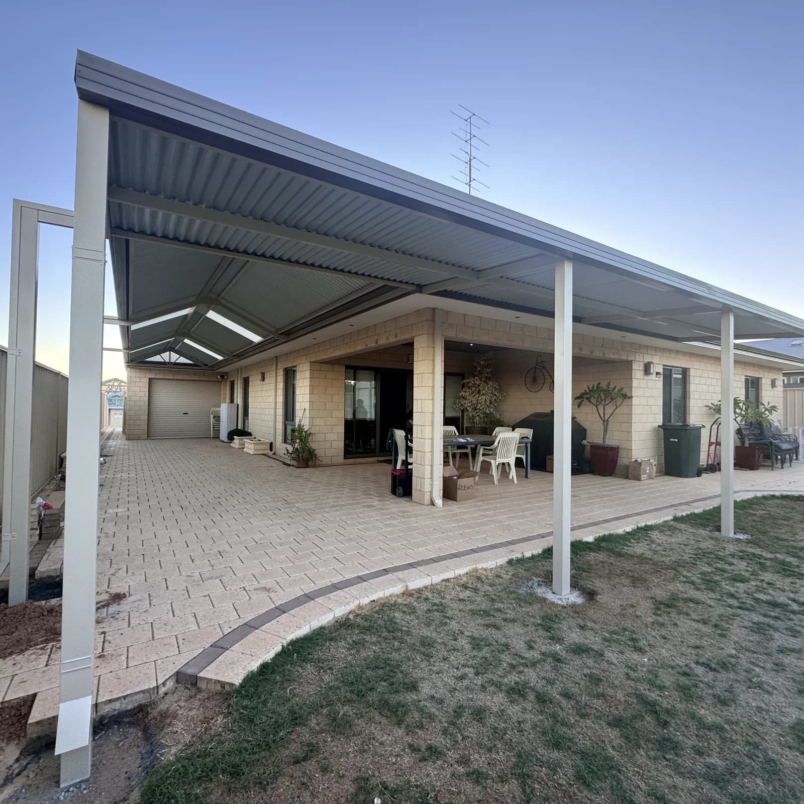 A flat roof patio over a paved alfresco, its single fall running away from the house