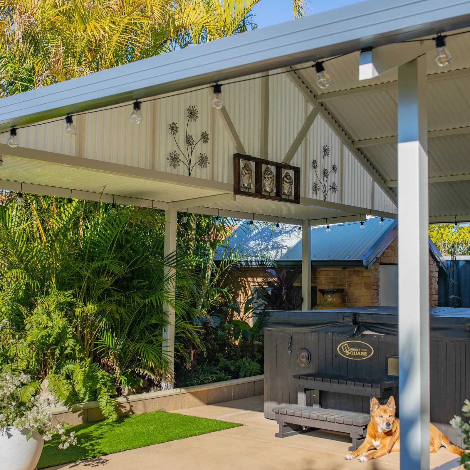 A gable patio over an outdoor kitchen and lawn, with track lighting fixed under the ridge