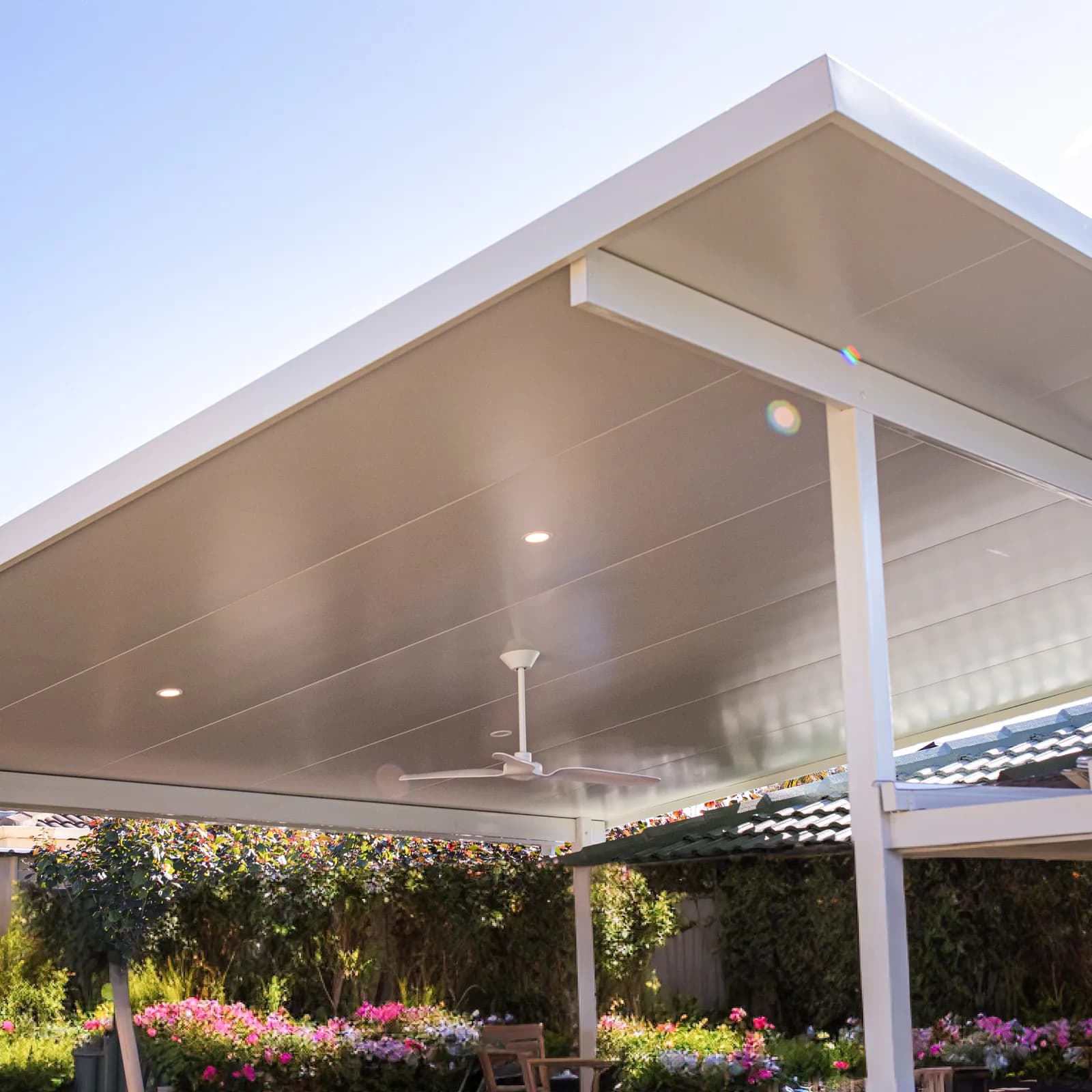 A white gable patio with a high pitched ceiling, a ceiling fan and downlights, over a garden in Perth
