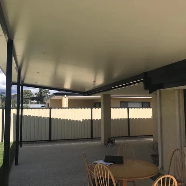An insulated flat roof patio over a paved area with an outdoor dining setting, flat white ceiling above