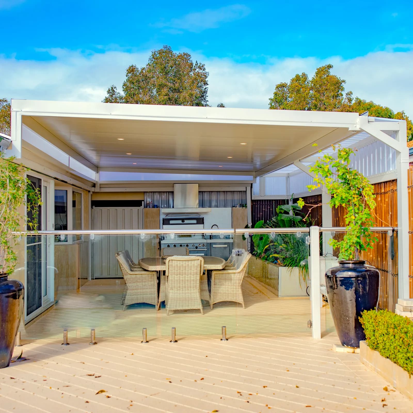 A raised flat patio over an outdoor kitchen and dining setting, lifted high above the house gutter