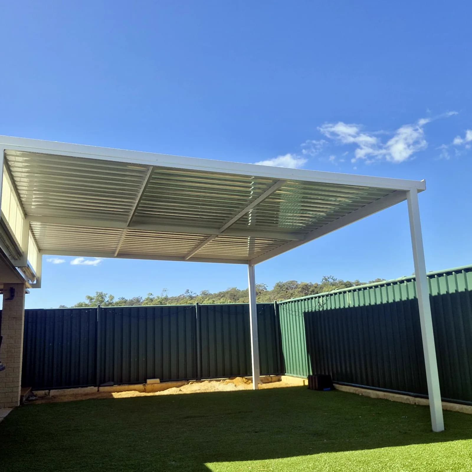 A raised flat patio in white Colorbond over a lawn, the roof lifted clear of the house eaves