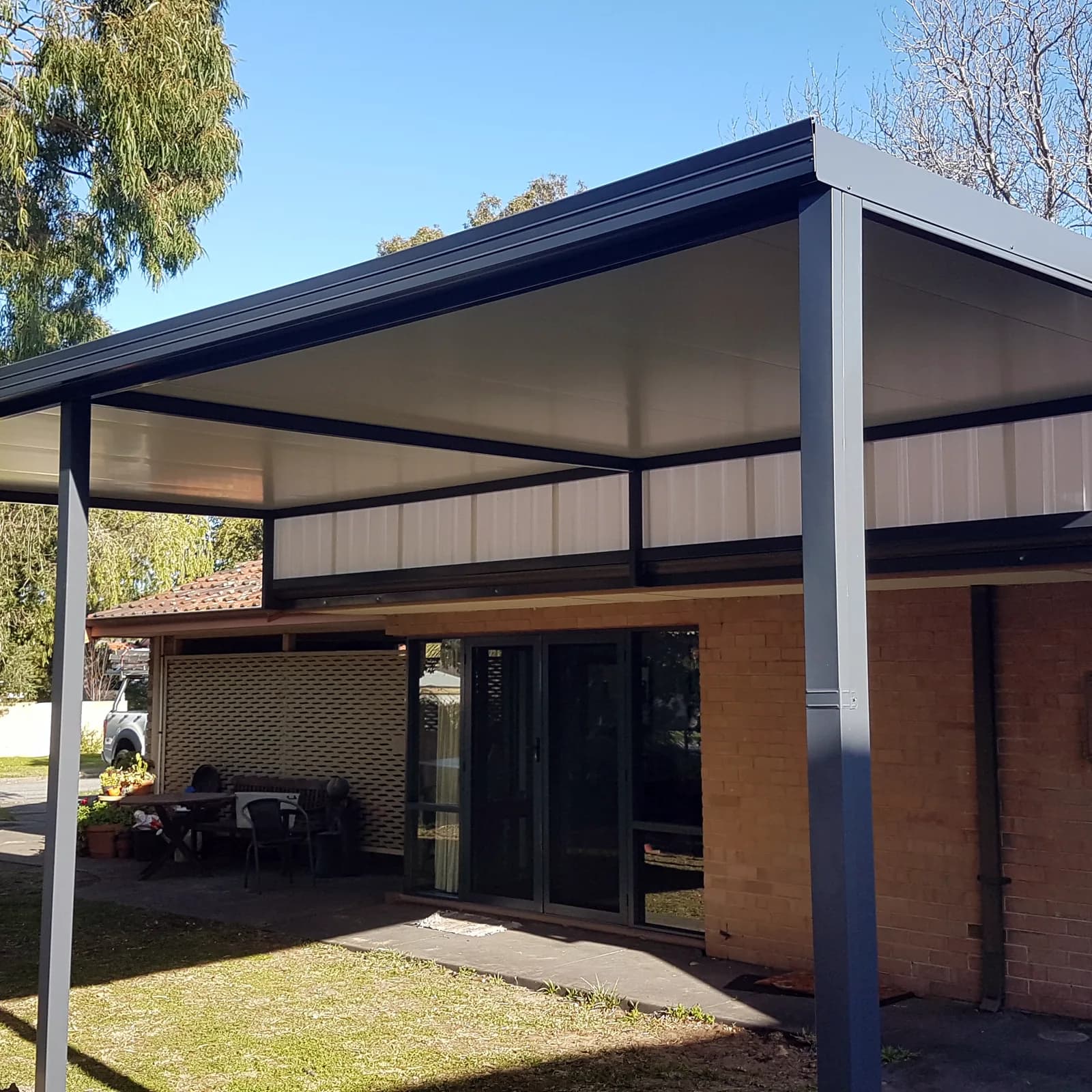 A raised flat patio in dark Colorbond across the back of a Perth home, set above the roofline