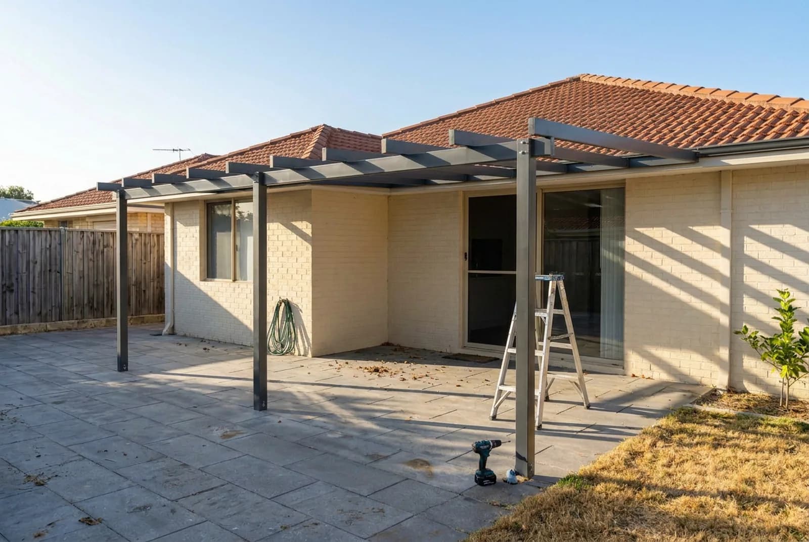 A patio frame bolted up with the sky still showing through, no roof sheets on yet